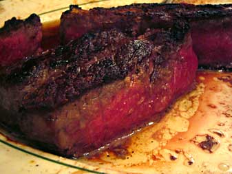 1991 Ford Bronco - Close-up of a cooked steak with a red interior, served on a plate with its juices.