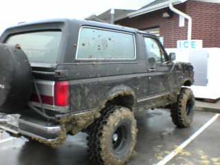 1991 Ford Bronco - A muddy 1991 Ford Bronco is parked next to an ice machine, showing off its off-road capabilities.