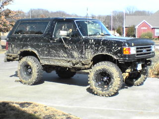 1991 Ford Bronco - This lifted 1991 Ford Bronco is heavily covered in mud, suggesting recent off-road use.