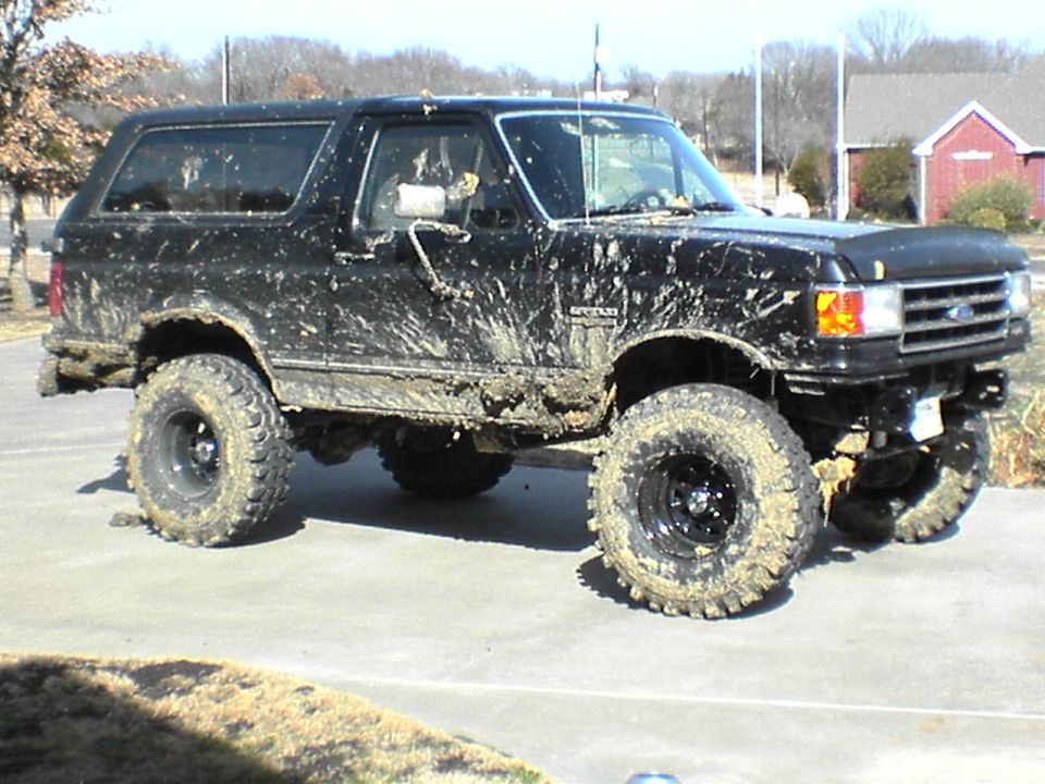 1991 Ford Bronco covered in mud, lifted suspension, off-road tires