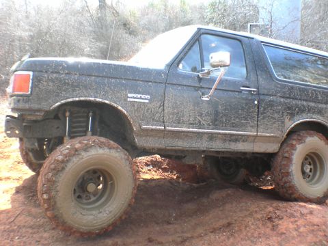 1991 Ford Bronco - This 1991 Ford Bronco is shown off-roading on a dirt trail, covered in mud.