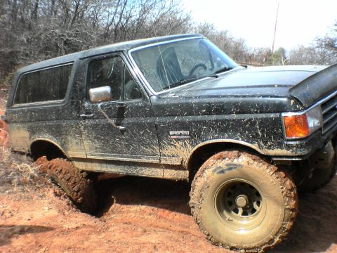 1991 Ford Bronco - This 1991 Ford Bronco is deep in the mud, showing its off-road capabilities.