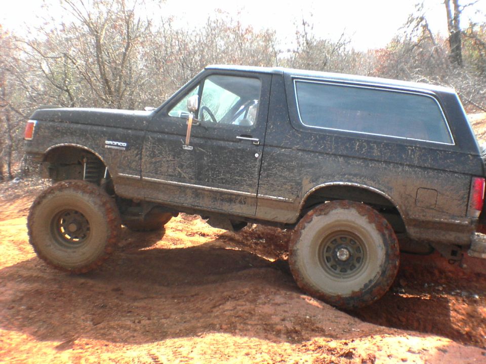 1991 Ford Bronco on a dirt trail, tires covered in mud