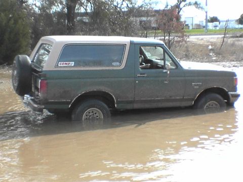 1991 Ford Bronco - This 1991 Ford Bronco navigates through a shallow body of water, with its side profile clearly visible.
