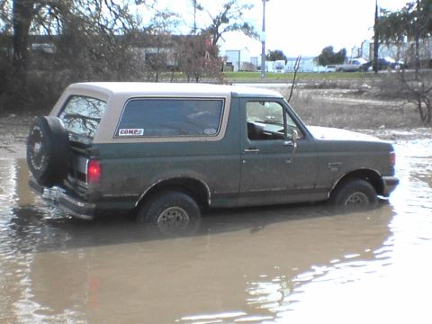 1991 Ford Bronco - This 1991 Ford Bronco is navigating through a flooded area, with its spare tire visible on the back.