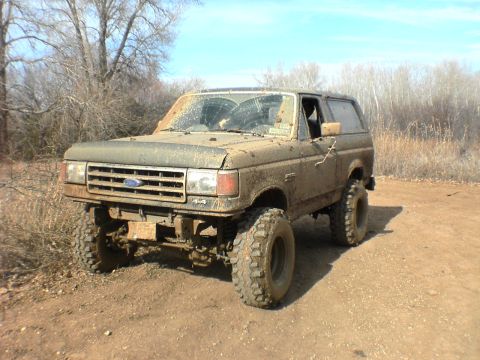 1991 Ford Bronco - This heavily soiled SUV is shown off-road, with its tires and body covered in mud.