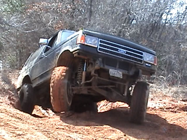 Black 1991 Ford Bronco climbing dirt hill, lifted suspension