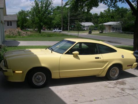 1978 Ford Mustang II - A yellow coupe with a distinctive fastback design is viewed from its side profile.