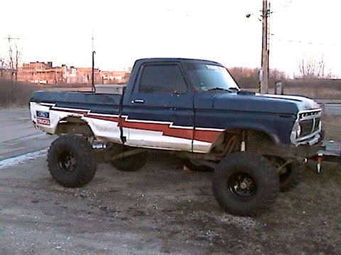 1977 Ford F-150 - This lifted 1977 Ford F-150 pickup features a distinctive blue, white, and red stripe graphic along its side.