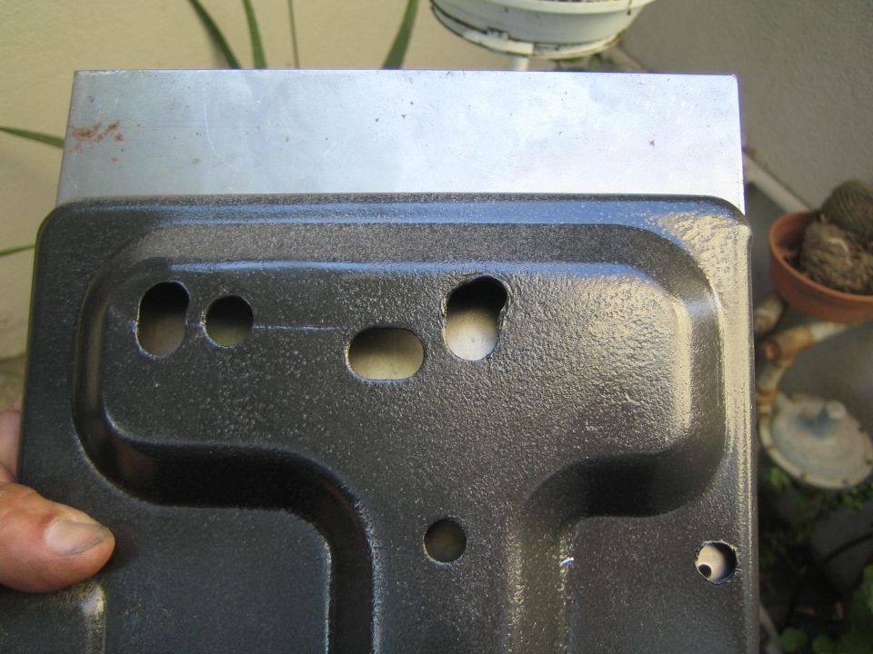 Hand holding a black textured-coated stamped metal tray with mounting holes