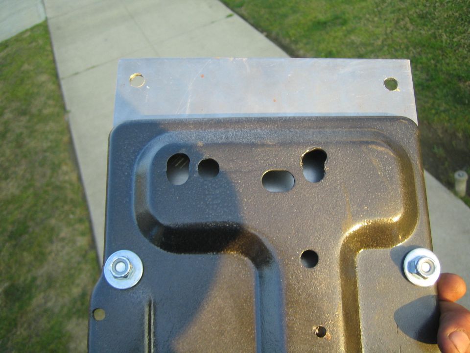 Black coated stamped metal tray bolted to a flat plate, held over a sidewalk
