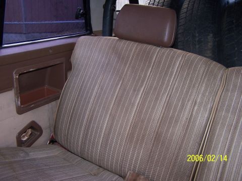 1984 Toyota 4Runner - The interior of a vehicle shows a striped fabric seat and a storage compartment on the side panel.