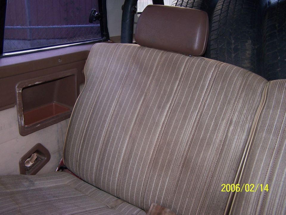 Back seat and interior panel of a vehicle. Spare tire visible behind headrest