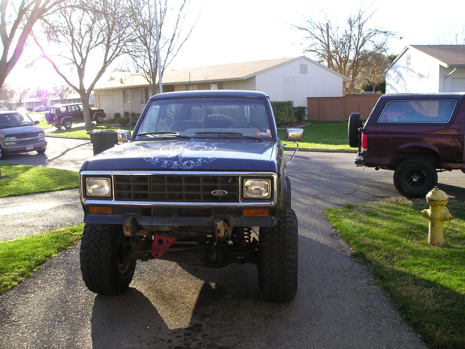 Front view of a lifted dark blue Ford SUV with bumper removed and exposed solid front axle