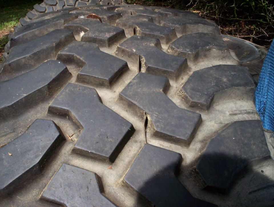 Close-up of a large, aggressive tire tread pattern. Supermotors.net logo visible