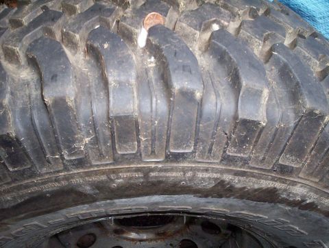 1991 Ford Bronco - Close-up of a tire's tread, showing wear and a lodged penny.