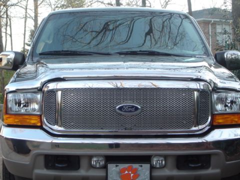 2001 Ford Excursion - The front of a Ford Excursion is shown, a chrome grille with the Ford emblem and clear headlights.