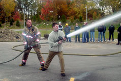 1985 Ford Bronco - A firefighter instructs a civilian on how to operate a fire hose during an outdoor demonstration.