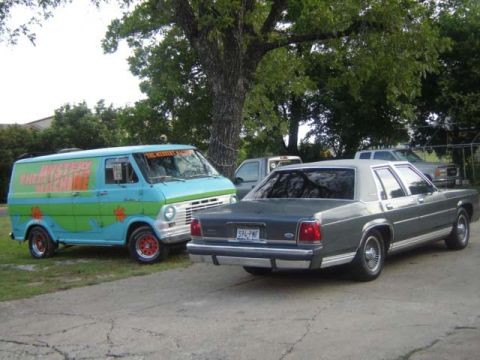 1988 Ford LTD Crown Victoria - A classic van, painted like the Mystery Machine, sits beside a sedan in a driveway.