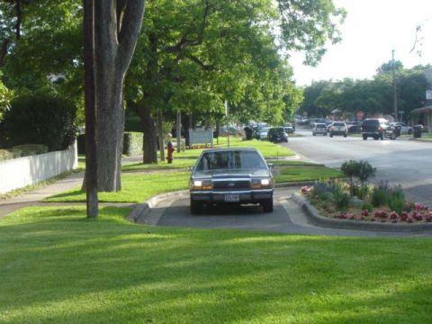 1988 Ford LTD Crown Victoria - A 1988 Ford Crown Victoria LTD sedan is seen from the front, parked on a grassy median in a suburban street.