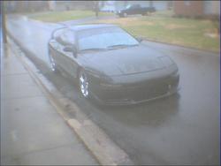 1993 Ford Probe - A dark 1993 Ford Probe sits on a wet street, possibly during rain.