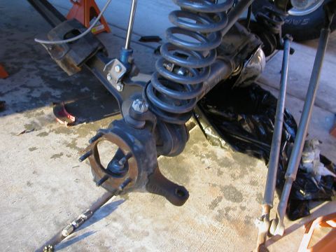 1984 Ford Bronco - The front suspension components of a vehicle are shown, with the wheel hub removed and the coil spring visible.