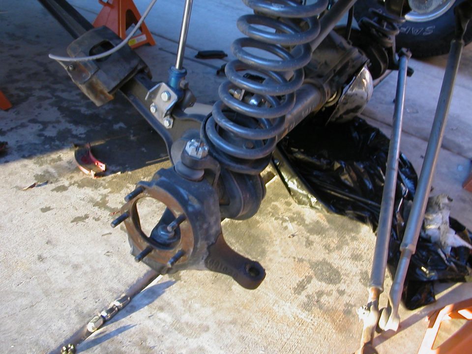 close-up of a vehicle's front suspension assembly, showing the hub, coil spring, and control arms