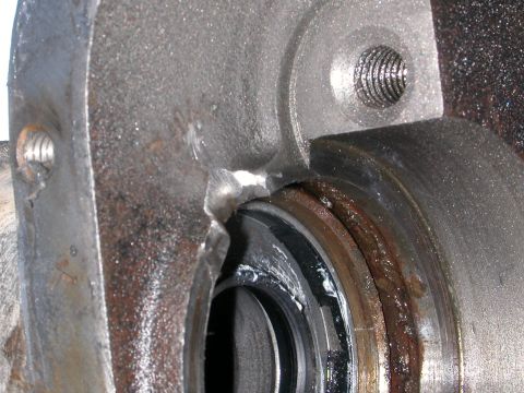 1984 Ford Bronco - Close-up view of a damaged metal component, possibly a hub or axle housing, showing a bearing and grease. A Supermotors.net logo is visible…