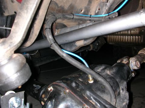 1984 Ford Bronco - Close-up of vehicle undercarriage components, including suspension and wiring, with a website logo.