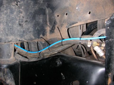 1984 Ford Bronco - Close-up view of the vehicle's undercarriage, highlighting installed tubing and hoses.