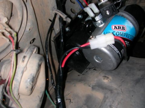 1984 Ford Bronco - Close-up of an ARB air compressor being installed, showing wiring and mounting hardware.
