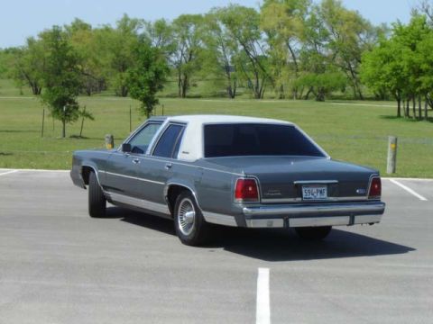 1988 Ford LTD Crown Victoria - The rear of a 1988 Ford Crown Victoria is visible, parked in an outdoor lot.