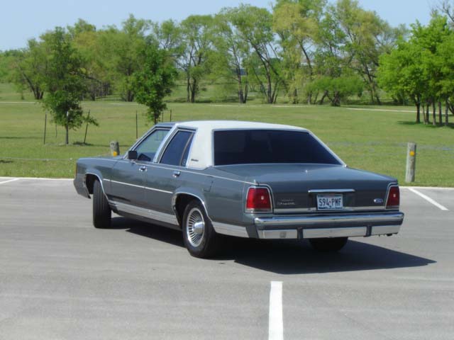 Gray 1988 Ford Crown Victoria parked on asphalt with trees in background