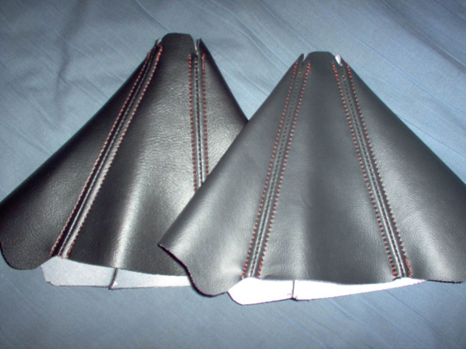Two black leather shift boot covers with red stitching on a blue fabric background