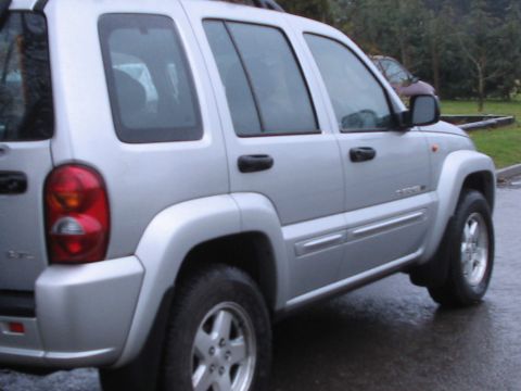1992 Ford Bronco - Side view of a silver Jeep Liberty, likely a 2002 model, parked outdoors.