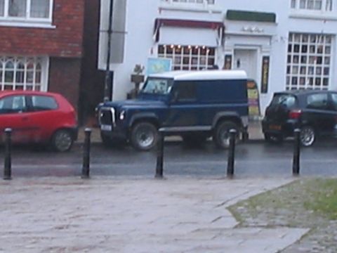 1992 Ford Bronco - A blue van with a white roof is parked on a street next to other vehicles.