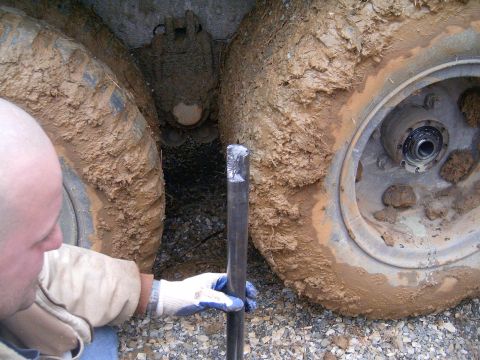 2006 Ford F1 - A person is working on the wheel hub of a vehicle stuck in mud.