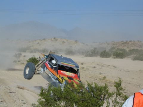 Off-road buggy 1215 landing hard nose-down off a desert berm as a spectator watches