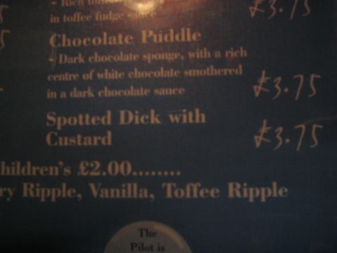 1992 Ford Bronco - A close-up of a menu board displays dessert options and their prices, including 'Chocolate Puddle' and 'Spotted Dick with Custard'.