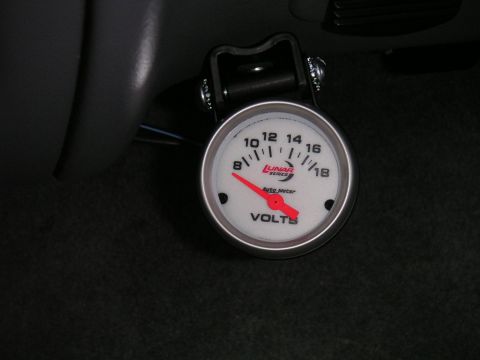 1994 Ford Bronco - Close-up of a Lunar Series Auto Meter voltmeter gauge installed in a vehicle.