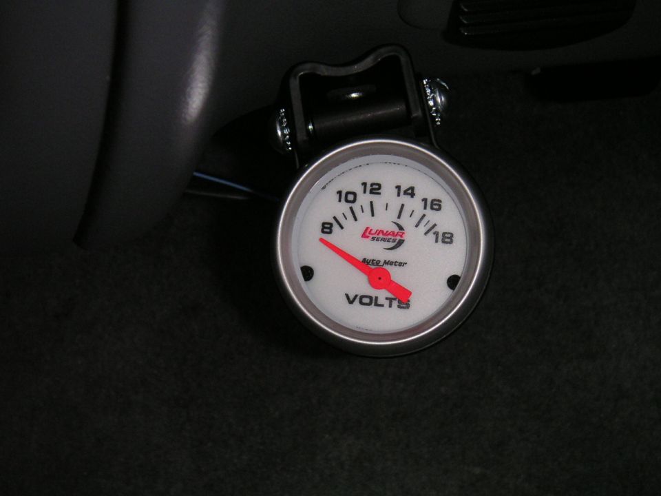 Auto Meter Lunar Series white-face volt gauge in black pod mounted under the dash
