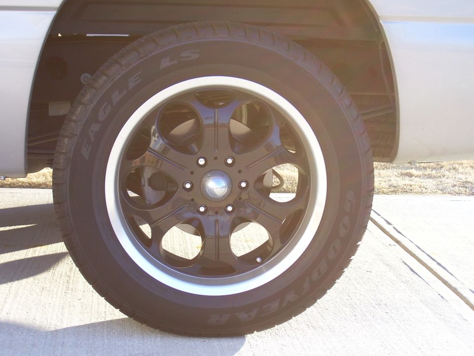 Black aftermarket wheel with Goodyear Eagle LS white-letter tire on silver vehicle