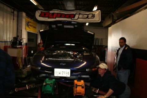 1996 Ford Probe - A dark blue coupe is positioned on a dynamometer with its hood open, possibly for engine work or testing.
