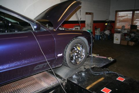 1996 Ford Probe - A purple car is on a dynamometer in a garage, with its hood open and wires connected.