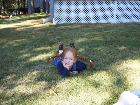 1979 Ford F-150 - A young child with freckles and braided red hair lies on a grassy lawn near a white lattice fence.