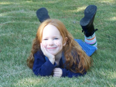 1979 Ford F-150 - A young girl with red hair and freckles smiles while lying on the grass.
