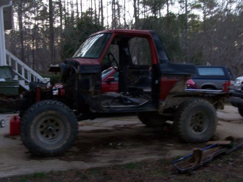 1979 Ford F-150 - A heavily modified pickup truck sits in a driveway, appearing to be mid-project with its doors and hood removed.