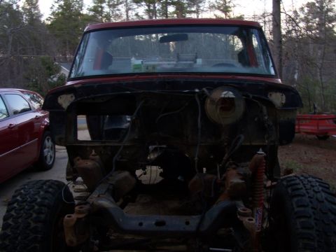 1979 Ford F-150 - The front of a red 1979 Ford F-150 is shown with its grille and headlights removed, revealing the engine bay.