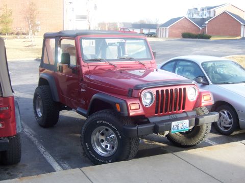 1998 Jeep TJ - A red 1998 Jeep TJ is parked in a lot next to a silver sedan and another Jeep.