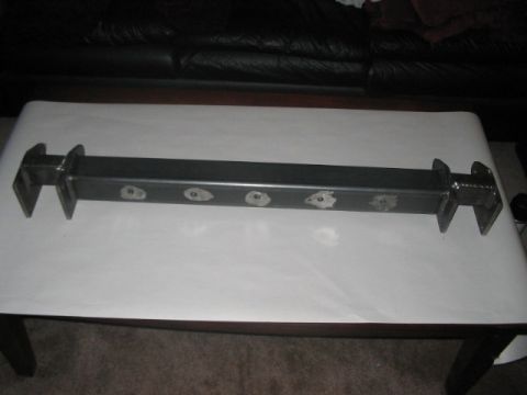 1991 Ford Bronco - A metal suspension component, likely for an off-road vehicle, is displayed on a table.